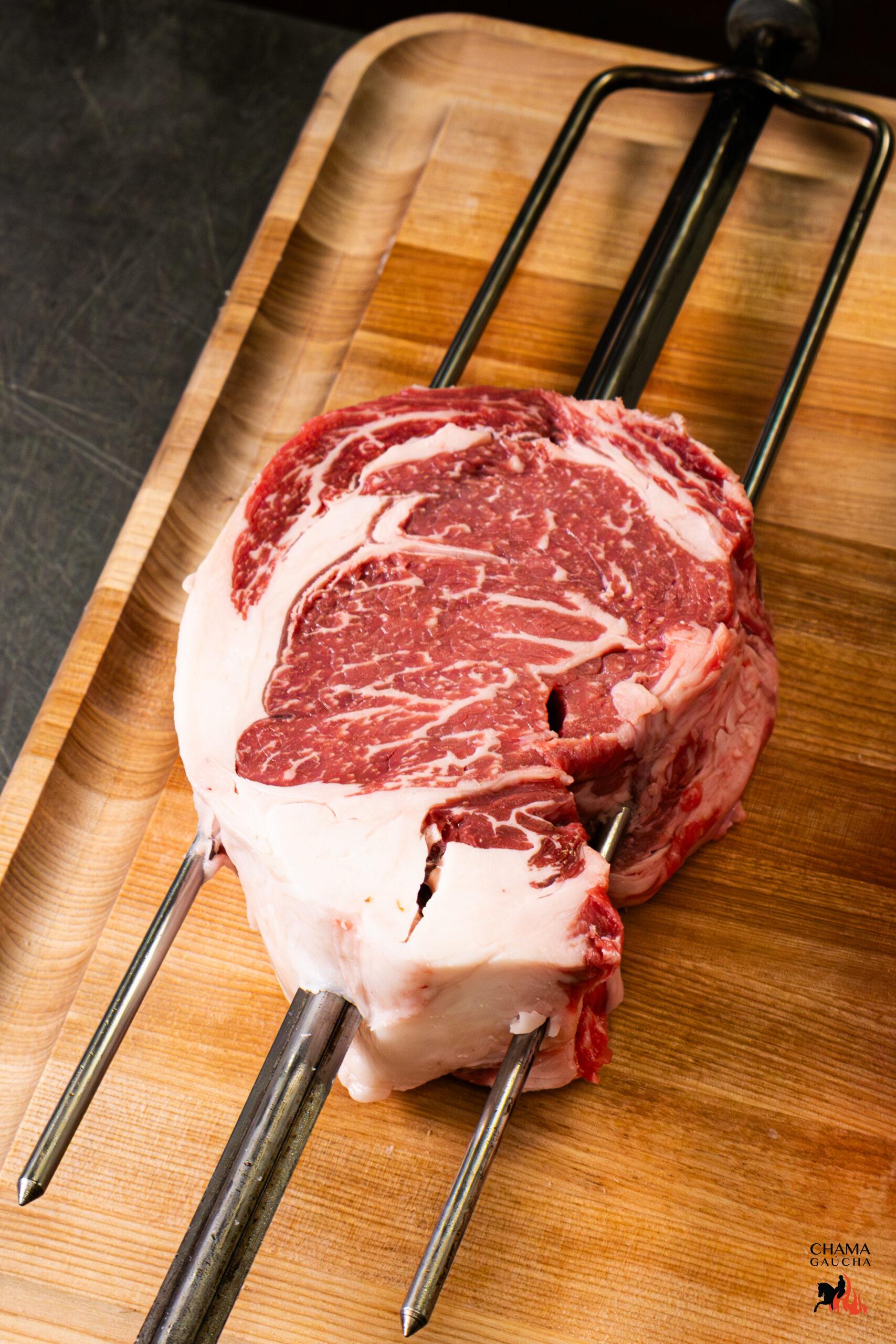 Raw USDA Prime ribeye on churrasco skewer prepared for grilling at Chama Gaucha Brazilian Steakhouse.