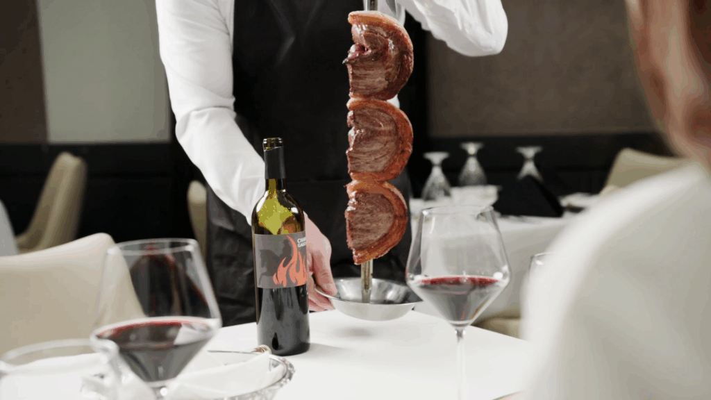 Gaucho carving fire roasted Picanha tableside with red wine served at Chama Gaucha.