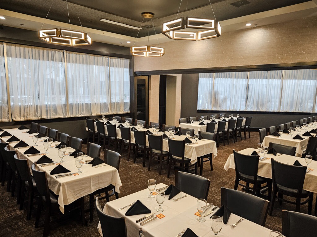 Large private dining room in Houston with multiple banquet tables, modern lighting, and floor-to-ceiling windows at Chama Gaucha
