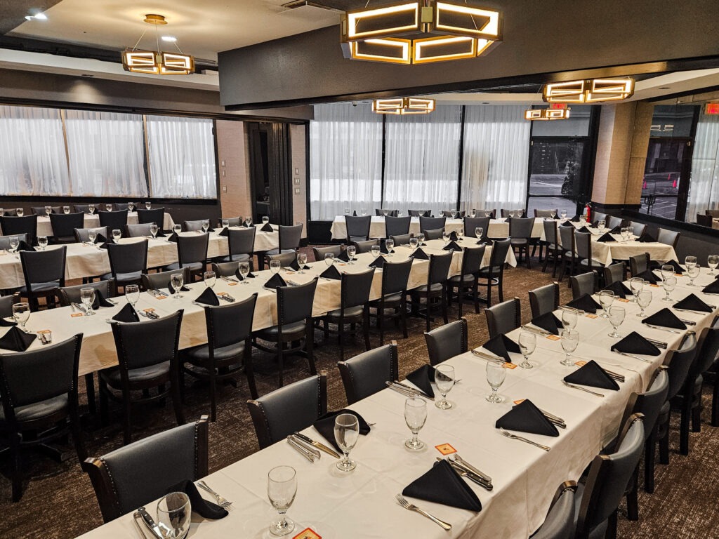 Houston banquet room with elegant table setup, modern chandeliers, and large windows for private dining at Chama Gaucha