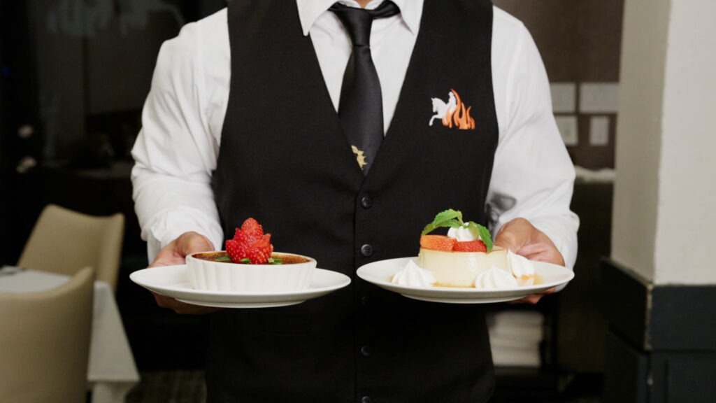 Chama server presenting crème brûlée and flan desserts at the table
